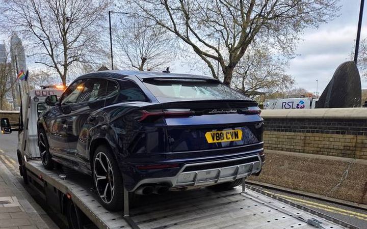 Black Lamborghini Urus SUV loaded on recovery truck flatbed