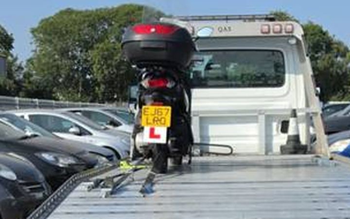 Red motorcycle secured on flatbed at vehicle auction and storage lot