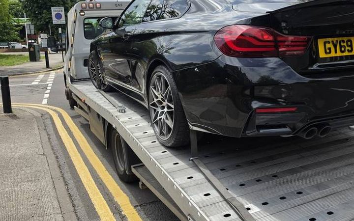 Black BMW 4-series loaded on recovery flatbed at street parking location