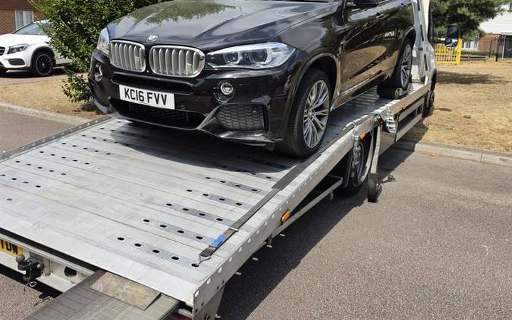 Black BMW X5 SUV loaded on recovery truck flatbed