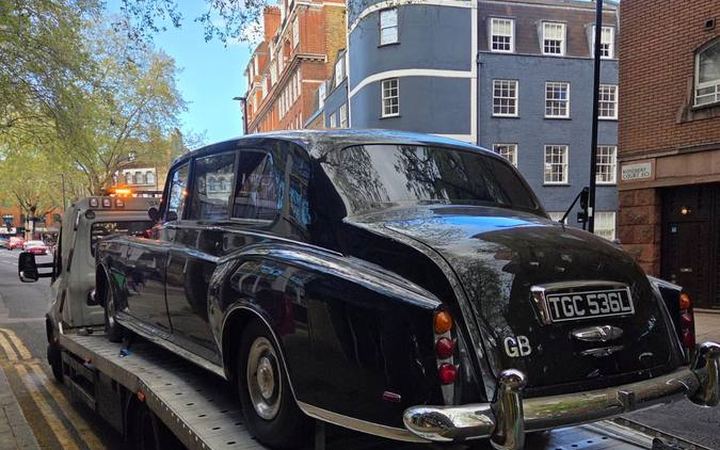 Classic black London taxi cab transported on recovery truck