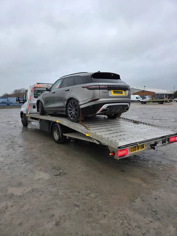 Range Rover sports car on recovery truck flatbed at storage facility
