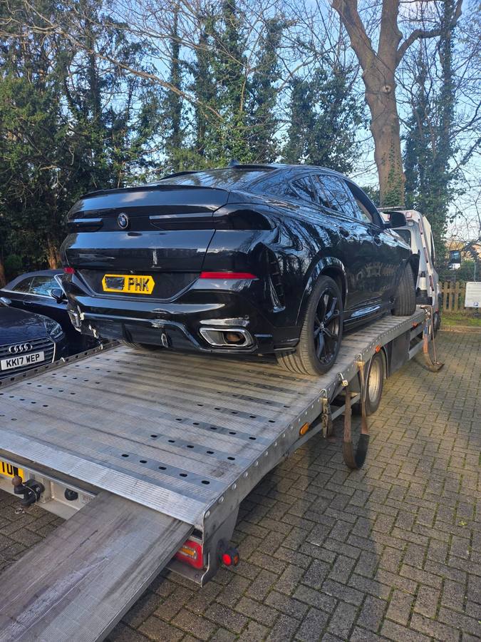 Black BMW performance coupe loaded on recovery truck flatbed