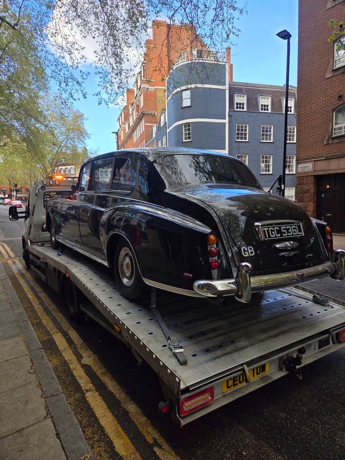 Classic black London taxi cab transported on recovery truck