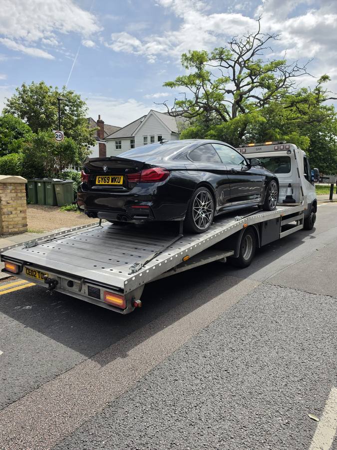 Black BMW performance sedan on recovery truck flatbed