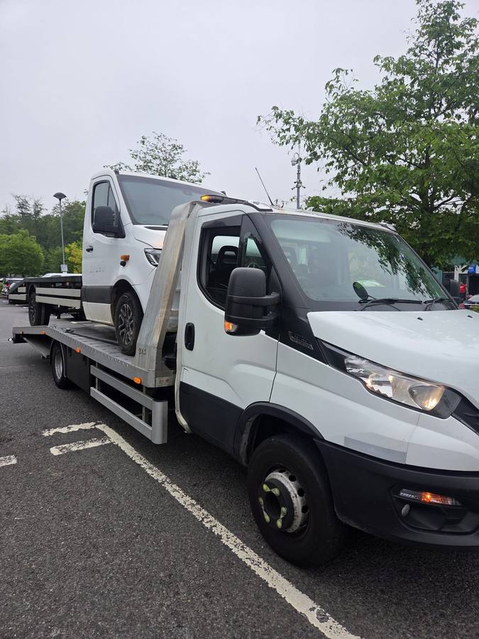 White Mercedes sports car transported on recovery truck flatbed