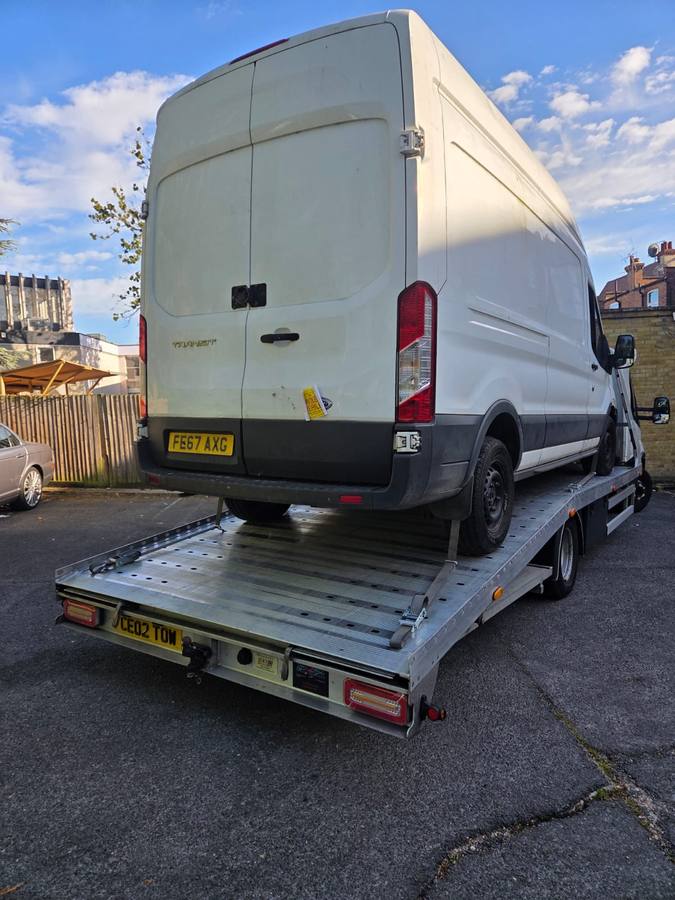 White Ford Transit commercial van recovered on truck flatbed