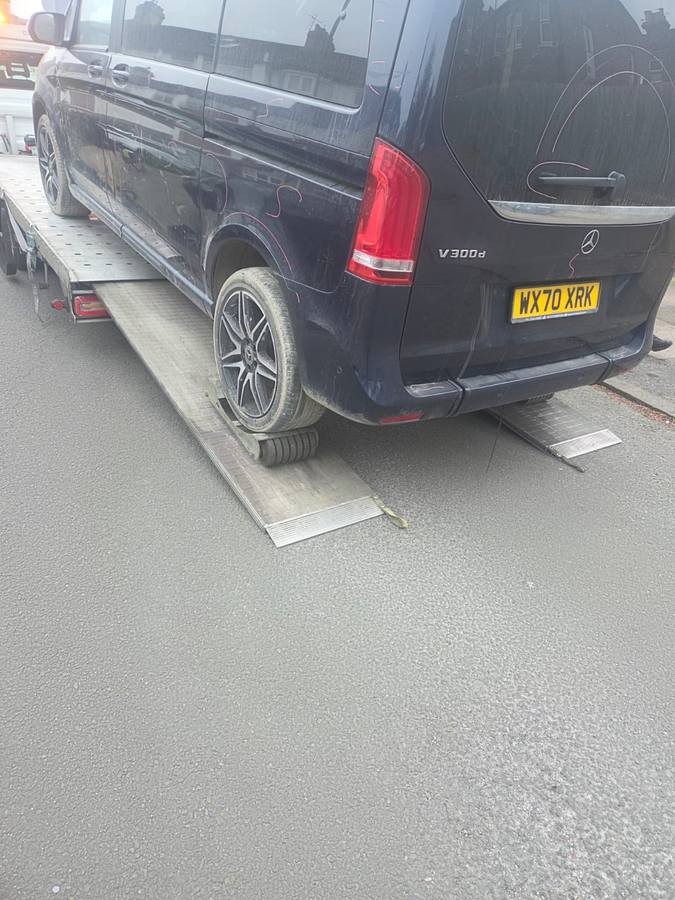 Black Mercedes commercial van loaded on recovery truck flatbed