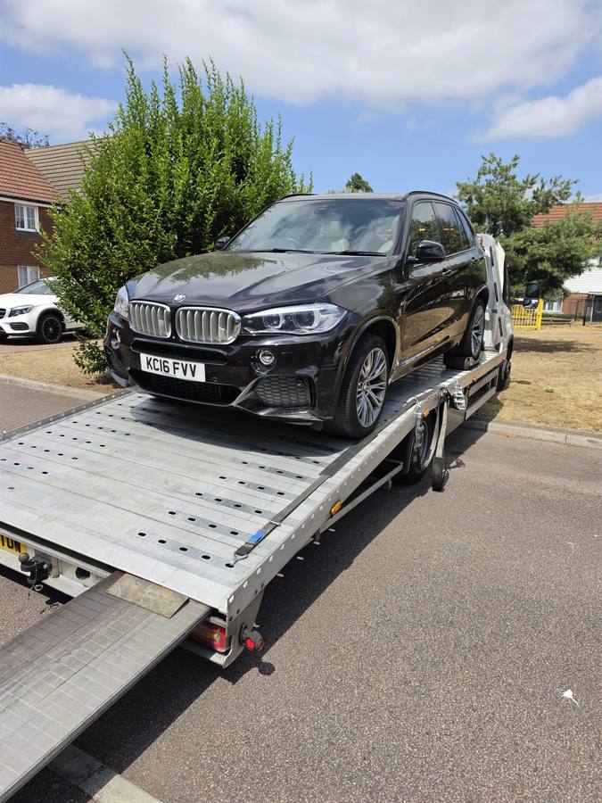 Black BMW X5 SUV loaded on recovery truck flatbed