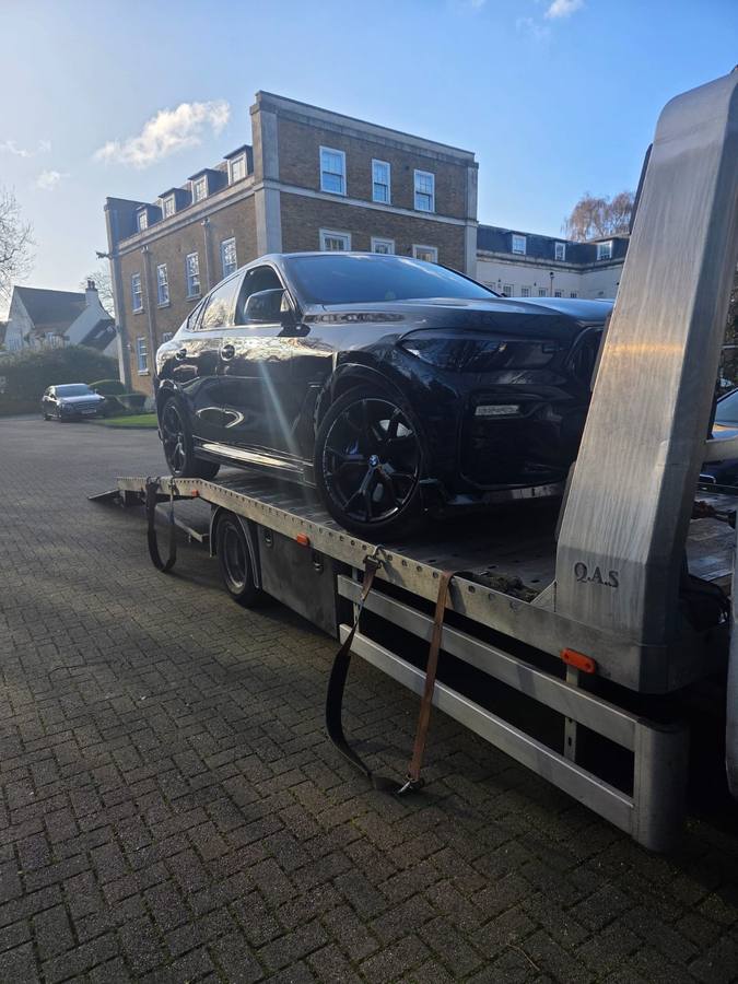 Black Jaguar luxury sports car on recovery truck flatbed