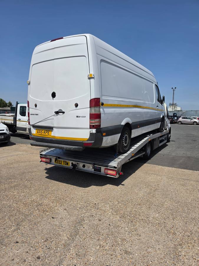 White Mercedes commercial van loaded on recovery truck flatbed