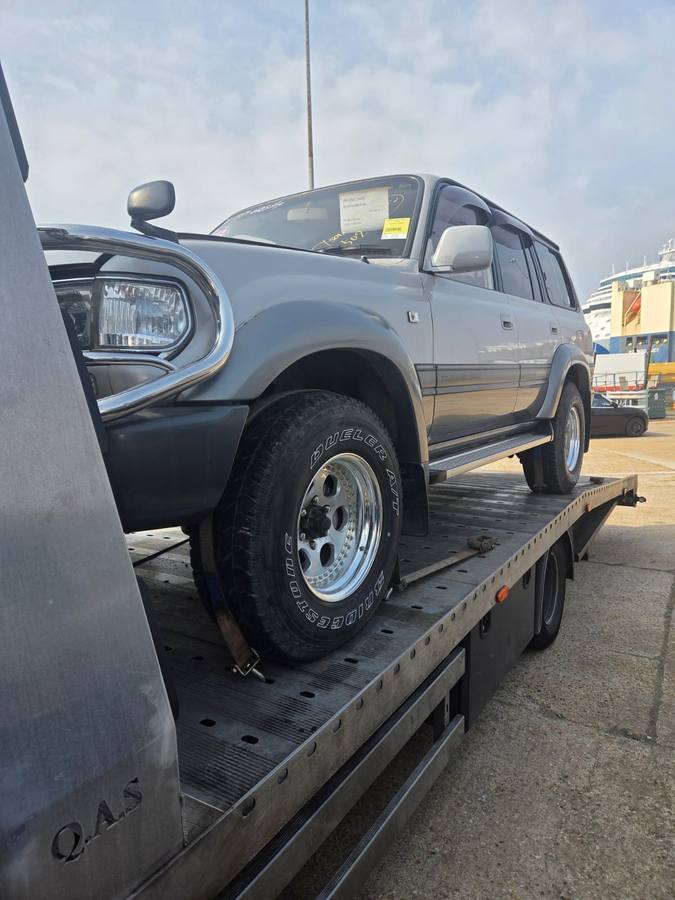 Grey vehicle secured on recovery flatbed at vehicle storage yard