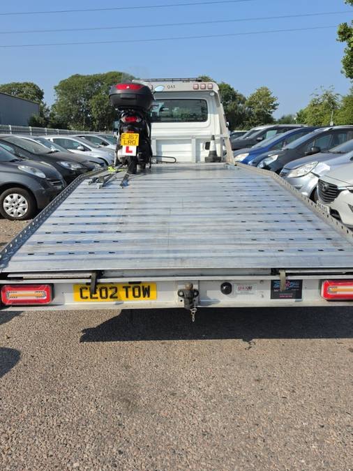 Red motorcycle secured on flatbed at vehicle auction and storage lot