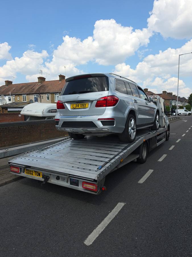 Silver Nissan Qashqai SUV transported on recovery flatbed in residential area