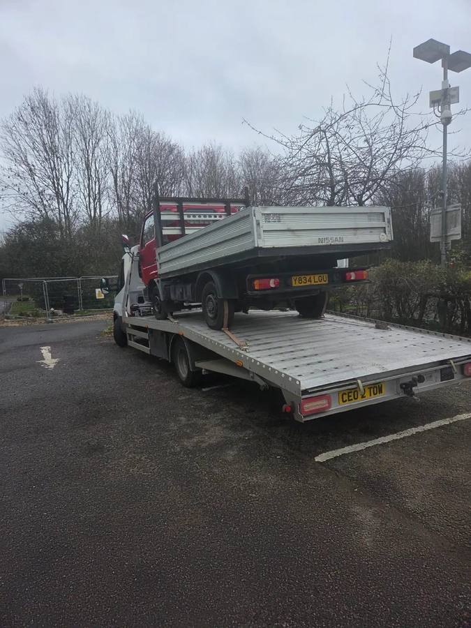 Red Nissan tipper truck on Tow 2 Tow recovery flatbed at winter industrial site