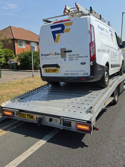 White PropFin branded commercial van on recovery flatbed in residential area