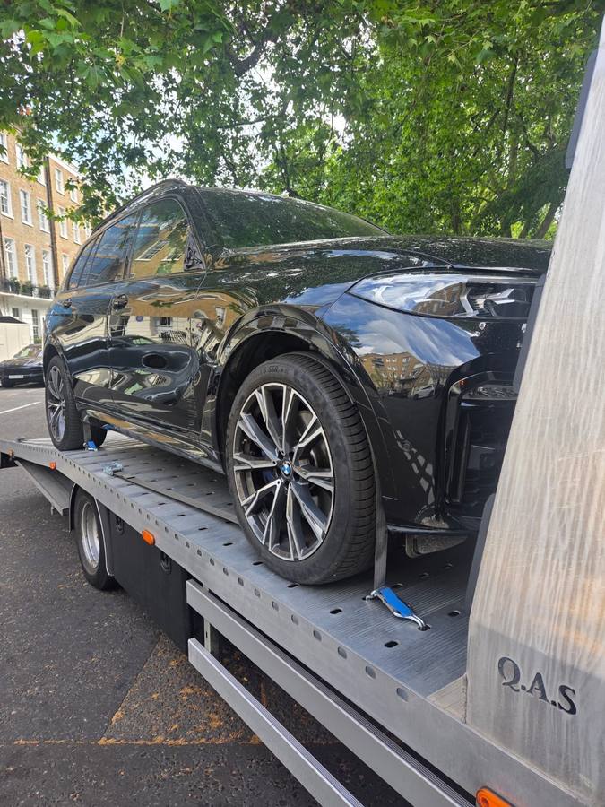 Black BMW X5 luxury SUV transported on recovery flatbed in London street