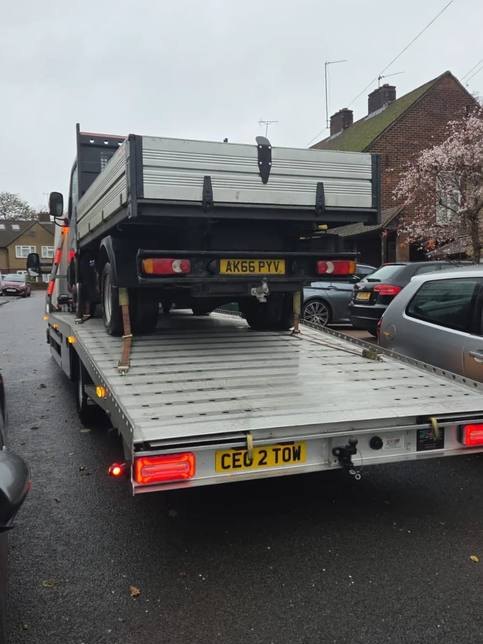 Black commercial truck transported on Tow 2 Tow recovery flatbed in street