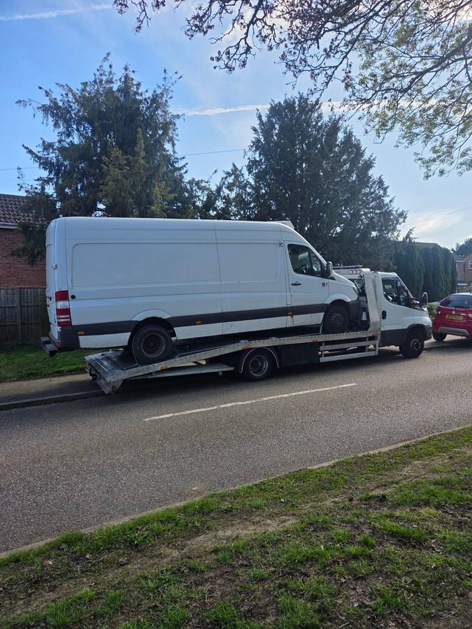 White Mercedes commercial van transported on flatbed in residential area